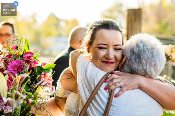 Il fotografo di matrimoni del Colorado ha creato questa immagine da una casa privata, Lafayette, Colorado, mentre la sposa abbraccia la nonna dopo la cerimonia