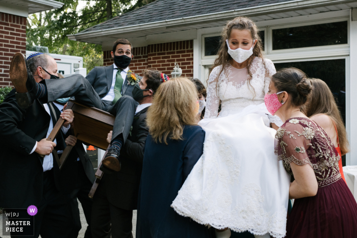 Imagem mostrando A noiva e o noivo são levantados em cadeiras para comemorar logo após a cerimônia de casamento em Long Island, NY