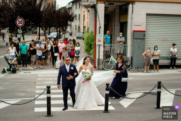 Hochzeitsfotografie vor der Kirche von San Andrea, Suisio (Bg) als Leute auf der Straße beobachten die Braut ankommen