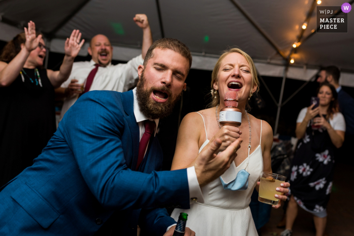 Durham, Connecticut, imagem de casamento de uma noiva e um noivo brincando e fingindo fazer karaokê na pista de dança