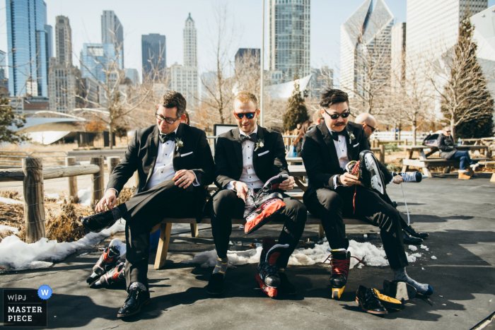 Photo by: <a href="https://www.wpja.com/contests/2020-v05/best-wedding-photographers/2606828">Edward Ciesielski - Berwyn Illinois</a> Maggie Daley Park, Chicago Groom & Groomsmen Lacing Up Their Skates in this wedding photo