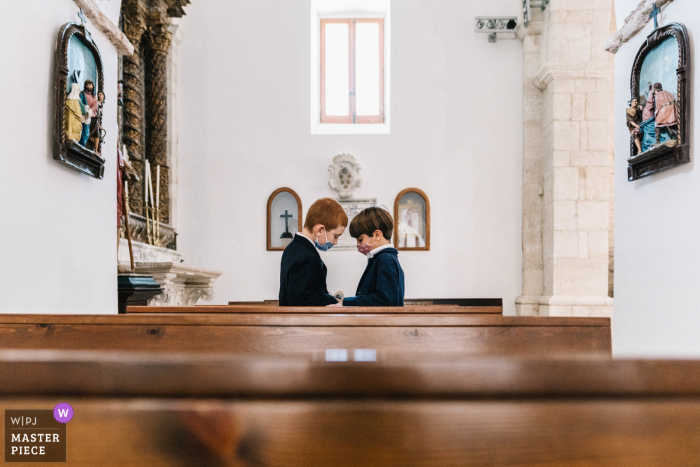 Kirchenhochzeitsfoto von zwei Jungen hinter Kirchenbänken in Apulien