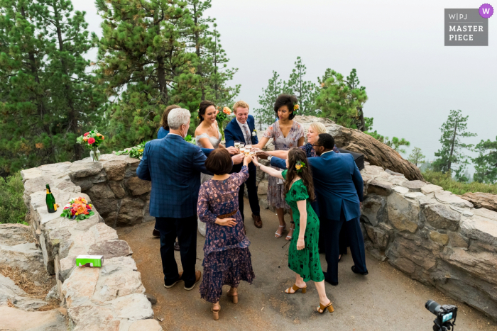 Incline Village, NV image of bride, groom and their family toasting together after an intimate elopement ceremony at the top of a mountain overlook shrouded in wildfire smoke