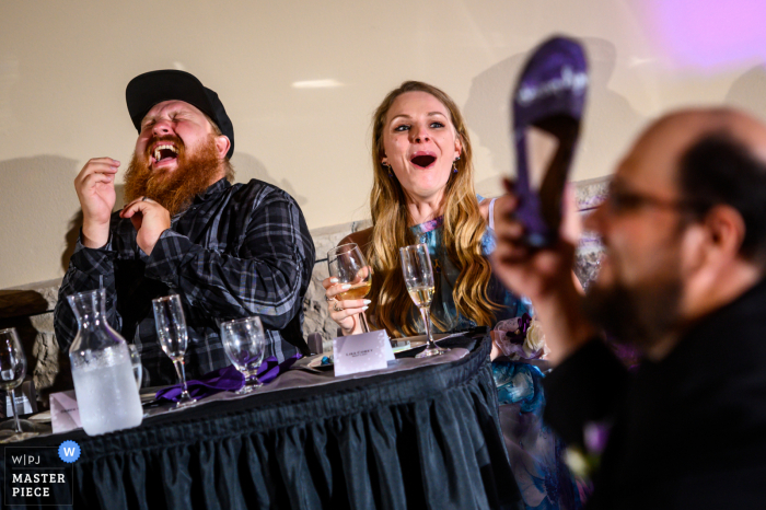 Imagen del lugar de la recepción nupcial de Tapestry House, Fort Collins, CO que muestra a los invitados a la boda estallando en risas mientras ven a los novios jugar el "juego de los zapatos"