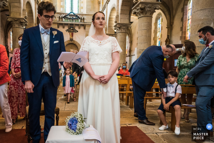 Trouwfoto van een Franse kerk waarop een kind te zien is dat geen plezier heeft tijdens de ceremonie voor de bruid en bruidegom