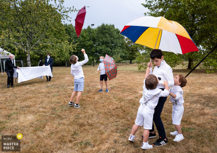 Bruiloftsfotografie van buitenevenement in Cromac - Tijdens de cocktail spelen kinderen met paraplu's