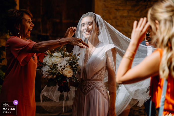 Auvergne-Rhône-Alpes Reception venue image of The bride putting on her veil, her mother laughs with emotion when she finds her