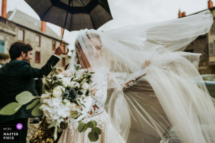 FR foto di reportage di matrimonio dalla Chiesa di Saint Flour mentre Il velo della sposa vola via