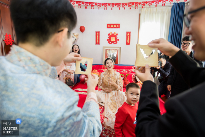 Chinese trouwfoto uit Hangzhou van de bruidegom en bruidsjonkers die de deurspellen voor de bruid spelen