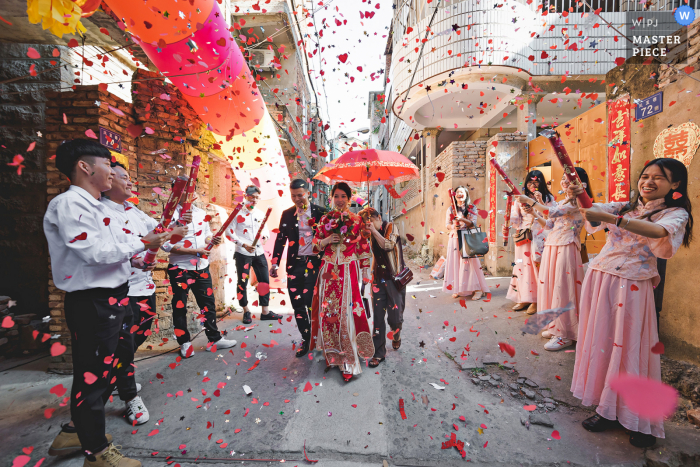 Quanzhou Fujian huwelijksfotografie van de bruid die onder confetti loopt met een rode paraplu