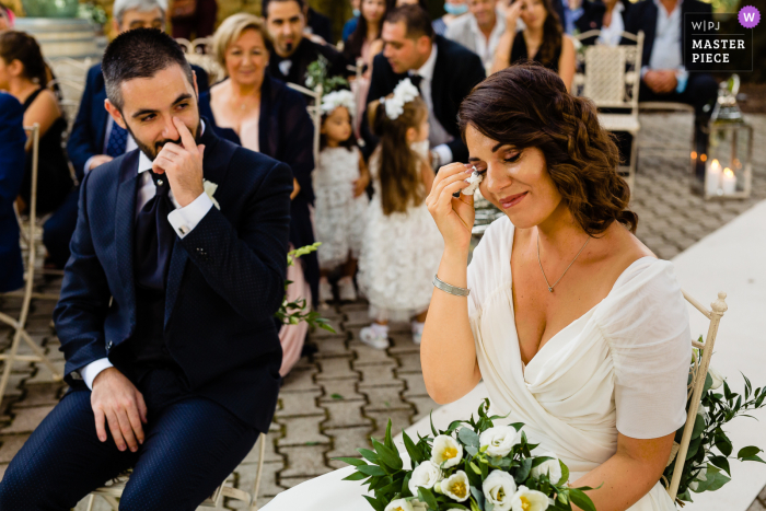 Fotografia de casamento de Borgo San Faustino, Orvieto - o noivo está olhando para sua noiva enquanto ela não consegue conter as lágrimas