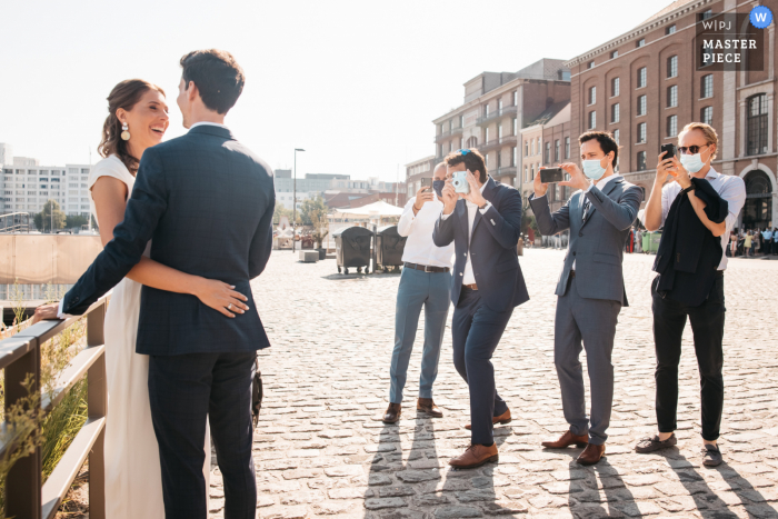 Trouwfoto uit Vlaanderen - Vrienden van de bruid en bruidegom poseren het paar om een ​​foto van hen te hebben op hun verschillende camera's