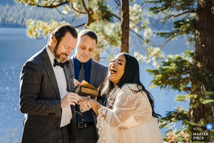 Wedding photo from California - Bride laughs with glee as her husband puts on her wedding ring. 