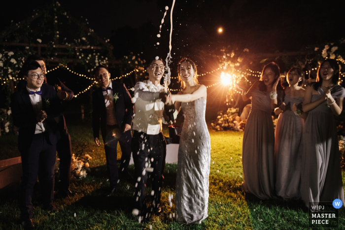 Foto de boda de Hangzhou, China. Hotel: la novia y el novio rocían champán en la fiesta posterior