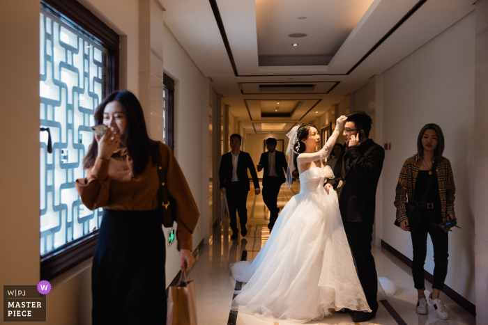 Trouwfoto uit Hangzhou, China. Hotel Terwijl de bruidegom druk bezig was met het beantwoorden van de telefoon, hielp de bruid de bruidegom bij het knippen van zijn haar.