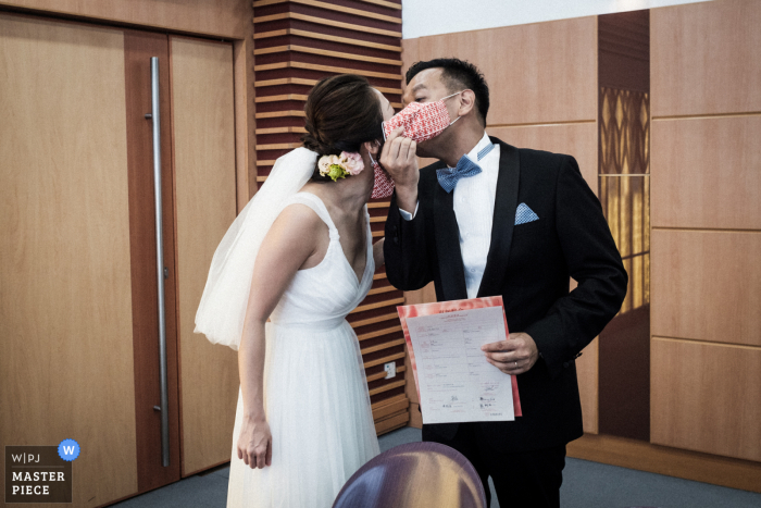 Fotografia de casamento do City Hall Marriage Registry, Hong Kong de O noivo tirando a máscara e beijando a noiva, após a conclusão da cerimônia