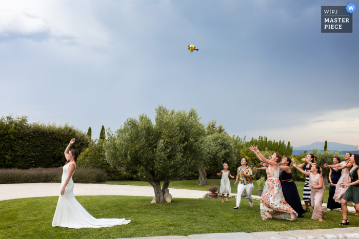 Auvergne-Rhône-Alpes outdoor wedding image of the bridal bouquet toss on the grass Auvergne-Rhône-Alpes outdoor wedding image of the bridal bouquet toss on the grass