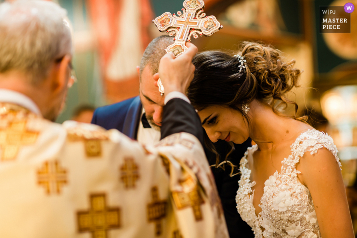 Fotografia di matrimonio in Bulgaria dalla chiesa "Vyzdvizhenie na svetiya kryst gospoden" a Sofia mentre il padre pone la croce sulle teste degli sposi