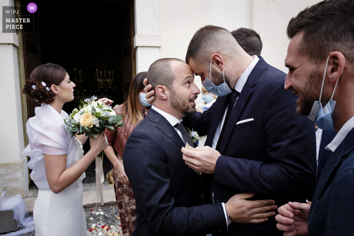 Włoskie zdjęcie ślubne przedstawiające Pana Młodego witającego przyjaciela po ceremonii w Chiesa di San Giulio w Vizzola Ticino