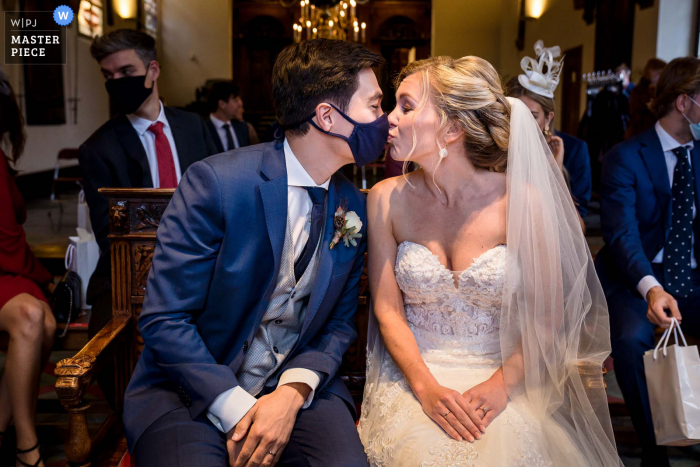 City Hall in Haarlem wedding photo capturing a moment after the ceremony where the groom has his facemask ready. The bride is giving him a kiss