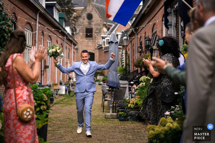 Naaldwijk, na Holanda, foto do casamento do noivo caminhando pelo beco para ver sua noiva. Ele está animado