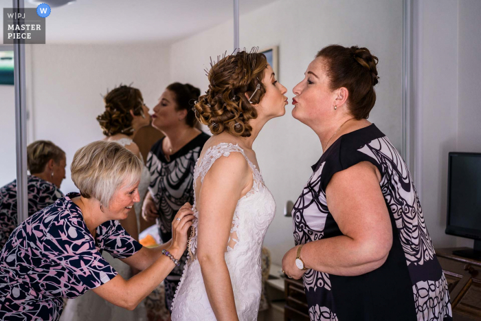 Immagine di preparazione del matrimonio olandese della sposa che si prepara e sua madre le sta dando un bacio amorevole