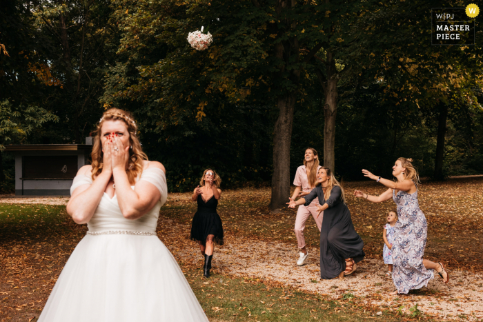 Foto de boda al aire libre de Amberes de la novia lanzando su ramo