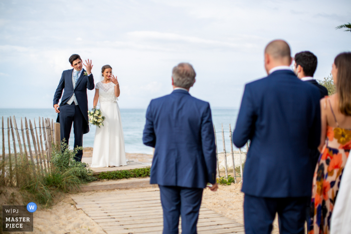 Les Portes-en-Ré fotografia de casamento na praia da noiva e do noivo exibindo seus anéis aos convidados após a cerimônia