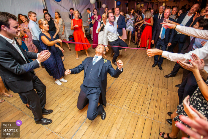 Photo by: <a href="https://www.wpja.com/contests/2020-v05/best-wedding-photographers/2610506">Florent Fauqueux - La Rochelle </a> France wedding photo from Doors in Ré - Ile de Ré of the Limbo during the dance party, in a frock coat