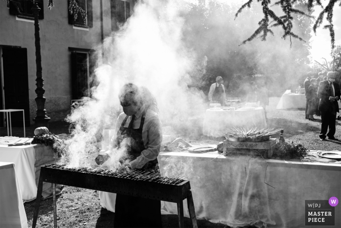 Villa Caproni, Vizzola Ticino, Italia Fotografía de boda de un marco lleno de humo mientras el cocinero hace barbacoas a la parrilla