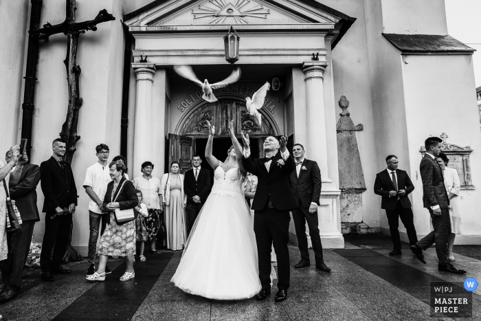 Huwelijksfotografie uit Andrespol Wedding Hall, Polen - het bruidspaar laat de vogels los nadat ze de kerk hebben verlaten