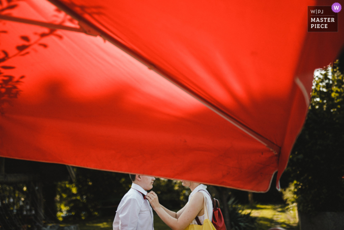 Foto de casamento de Zagreb, Croácia, de um homem recebendo ajuda com sua gravata