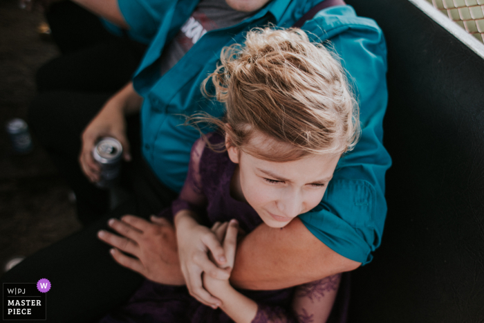 Wedding photography from the Thief River Falls, MN of a  young girl holds on to her dad on the "party trailer ride"