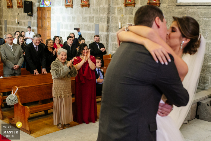 Hochzeitsfotografie von Igreja Matriz de Gramado von Braut und Bräutigam, die sich während der Innenzeremonie küssen