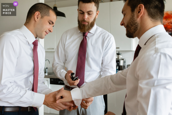 French groom is getting ready for the wedding with his team and he uses a stapler for his shirt 