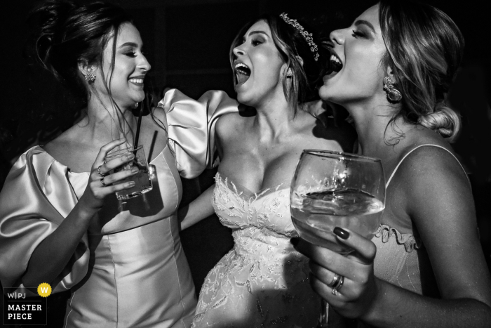 Imagen de boda en Villa Borguese Anápolis de la novia con dos amigas cantando en esta foto de recepción en blanco y negro