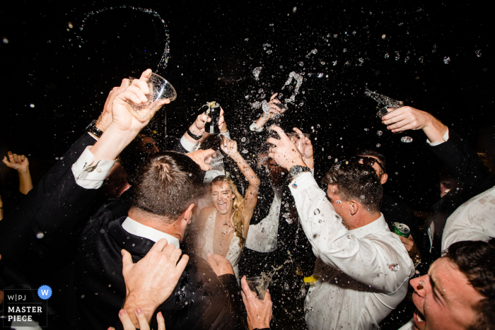 Imagem do casamento de Big Sky, Montana, da noiva e dos convidados em uma festa com bebidas espirrando acima de suas cabeças