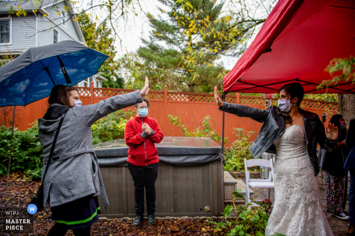 Rockville Backyard Wedding photo of bride and one of her best friends go in for a socially distanced hi-five at the reception Rockville Backyard Wedding photo of bride and one of her best friends go in for a socially distanced hi-five at the reception