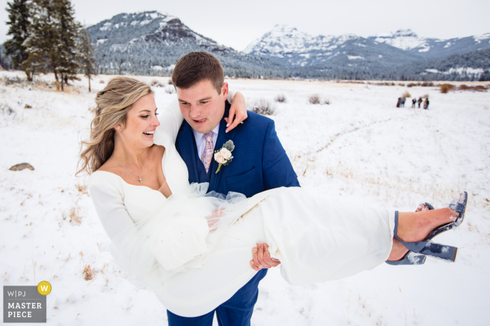 Winterhochzeitsfotografie des Yellowstone-Nationalparks im Schnee von Braut und Bräutigam während der Rezession