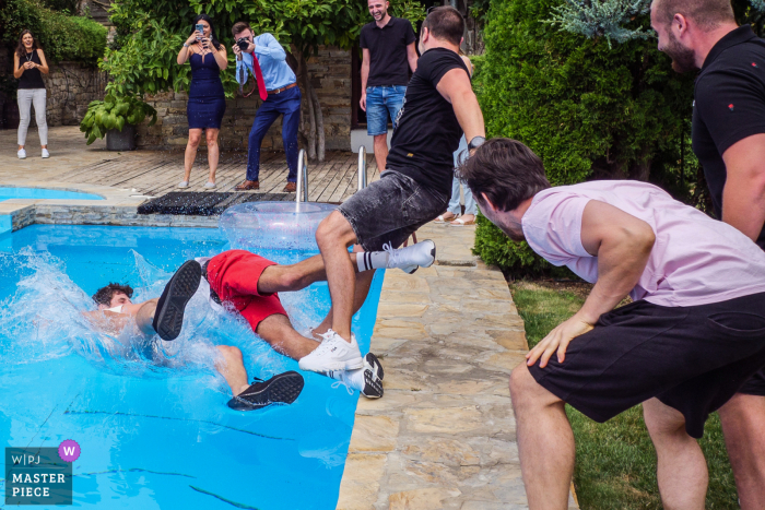 Trouwfotografie in Mogilovo, Bulgarije waarop te zien is hoe de vrienden van de bruidegom de beste man in het zwembad gooien voor de voorbereiding