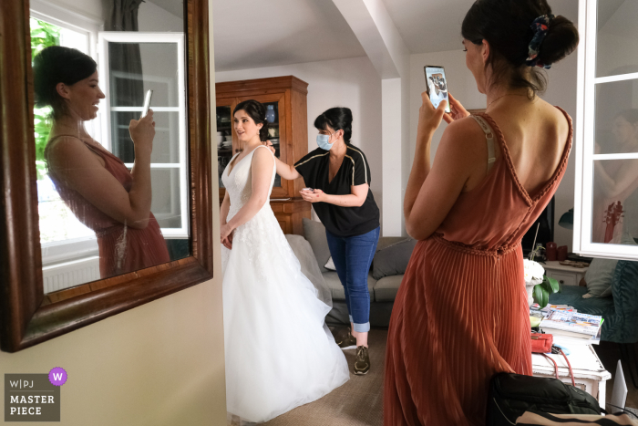 Fotografia de casamento de Limoges com a noiva se preparando e pessoas ajudando e tirando fotos