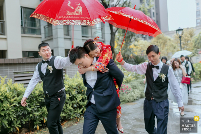 China fotografia de casamento em casa do costume do noivo carrega a noiva para o carro do casamento