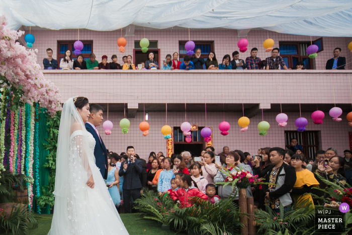 Foto do casamento do novo casal em casa na China e sua cerimônia de casamento no palco montado em seu pátio, e os moradores vieram assistir a cerimônia