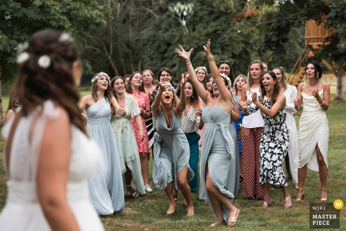 Domaine de Pécarrère, France wedding photo of the outdoor garden flower bouquet toss on the lawn Domaine de Pécarrère, France wedding photo of the outdoor garden flower bouquet toss on the lawn