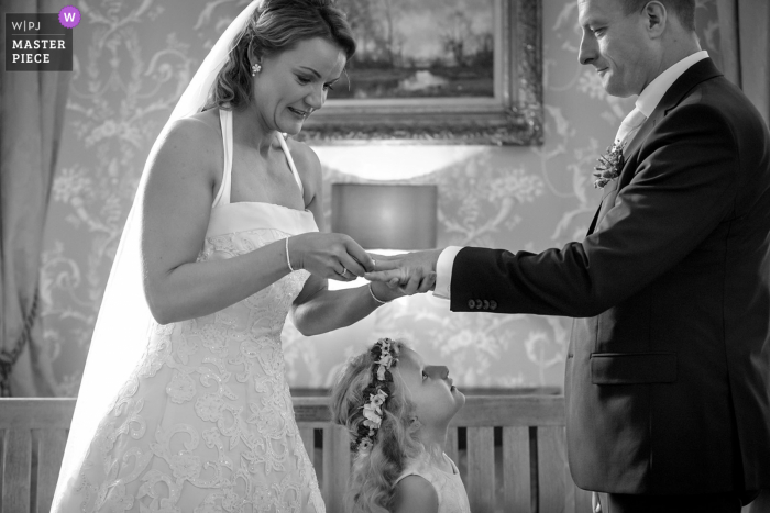 Kasteel Hackfort, Vorden Hochzeitsfotografie zeigt das Blumenmädchen, das am Austausch von Eheringen durch ihre Mutter und ihren Vater teilnimmt