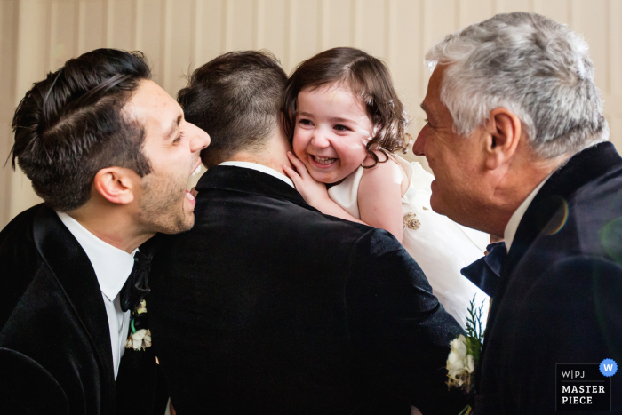 Foto de casamento da Ryland Inn Coach House, em Nova Jersey, mostrando a menina das flores rindo do avô e do tio