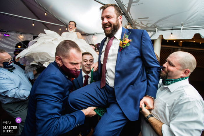 Desmond Hotel Malvern, Pensilvânia, fotografia de casamento mostrando o noivo levantado no ar pela hora com a noiva ao fundo