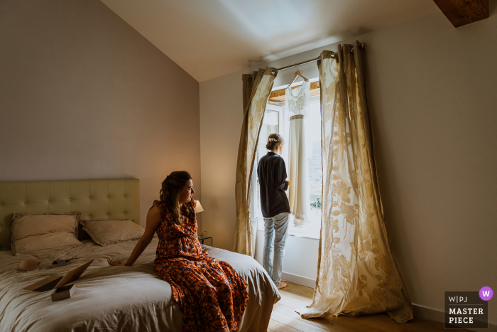 Auvergne-Rhône-Alpes Reception wedding photography created as The bride waits to get ready, she looks out the window to try to see her future husband