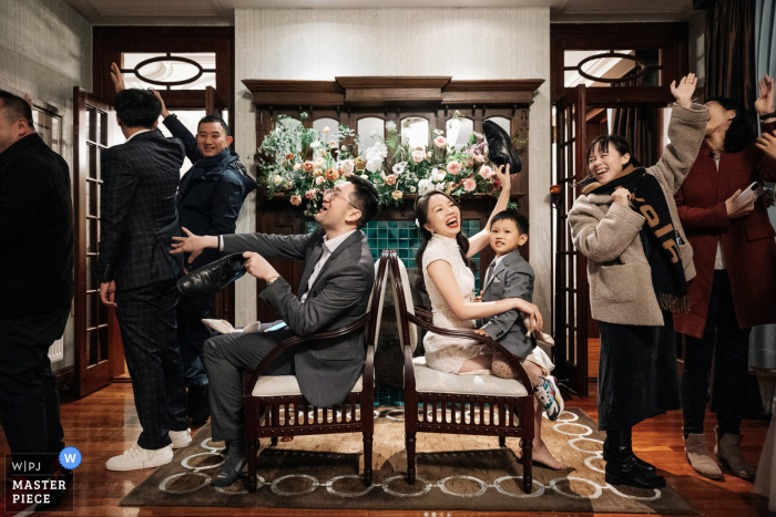 Foto de casamento em hotel em Xangai, China, ilustrando parentes e amigos jogando sapatos com os noivos