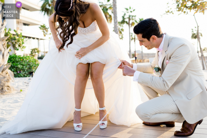 Nikki Beach Dubai fotografia di matrimonio dello sposo che aiuta la sposa a sistemare il suo vestito